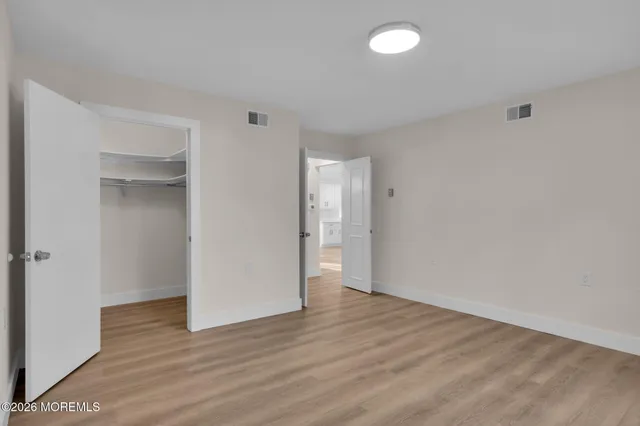 a view of an empty room with wooden floor and closet