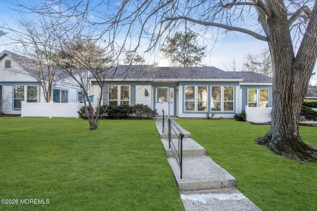 a view of house in front of a big yard with large trees and plants