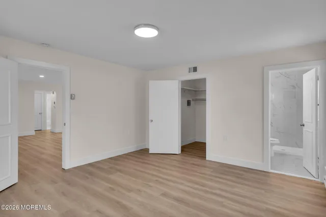 a view of an empty room with wooden floor and closet
