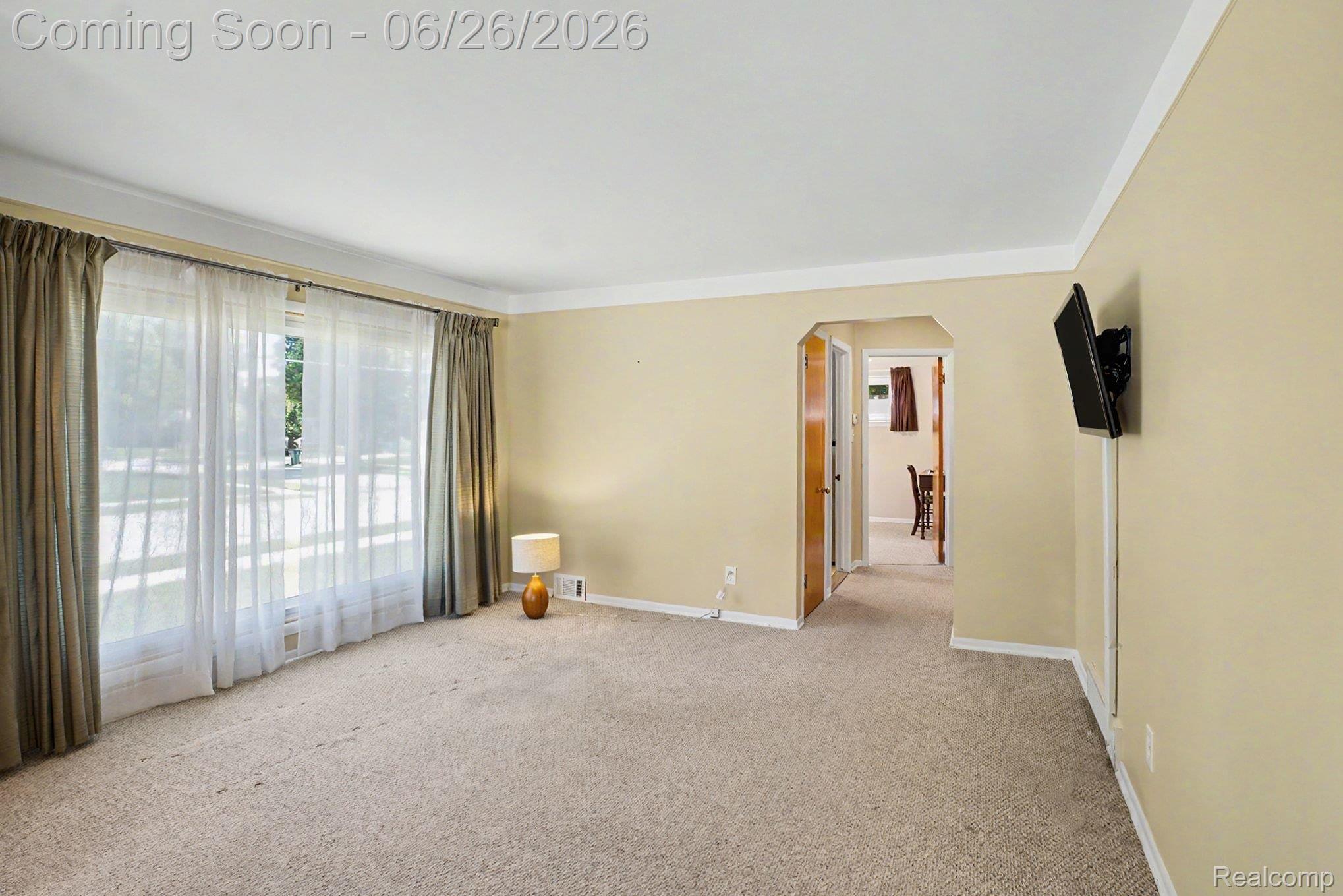 1209 Massoit Road Clawson, MI 48017 - Photo 8 of 25 Living area featuring expansive windows with sheers and drapery, neutral carpet, light-toned wall paint, and white crown molding