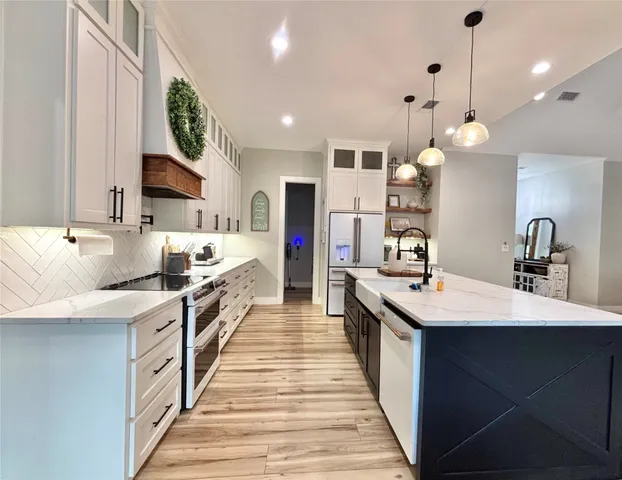 a large white kitchen with a large island oven a sink stainless steel appliances and cabinets