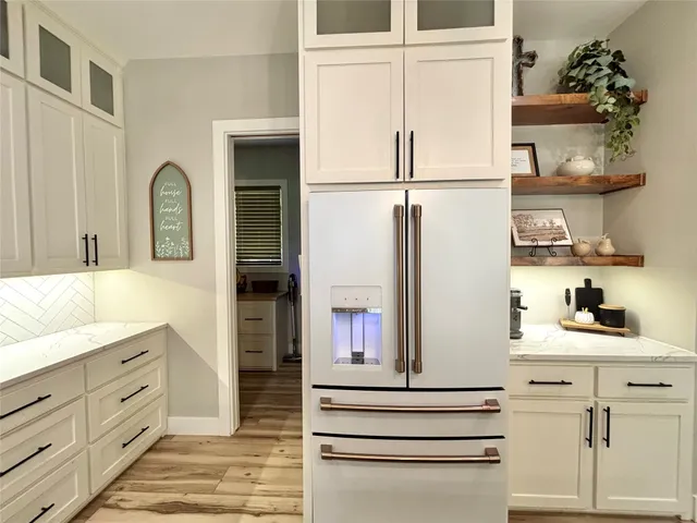 a kitchen with white cabinets and refrigerator