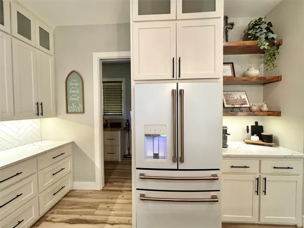 a kitchen with white cabinets and refrigerator
