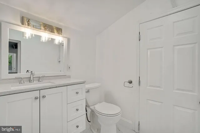 a bathroom with a granite countertop sink toilet and mirror