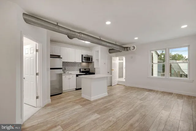 a kitchen with white cabinets and wooden floor