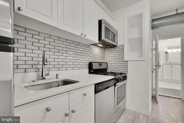 a kitchen with stainless steel appliances a sink dishwasher a refrigerator and cabinets