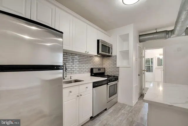 a kitchen with a sink dishwasher a refrigerator and a stove with wooden floor