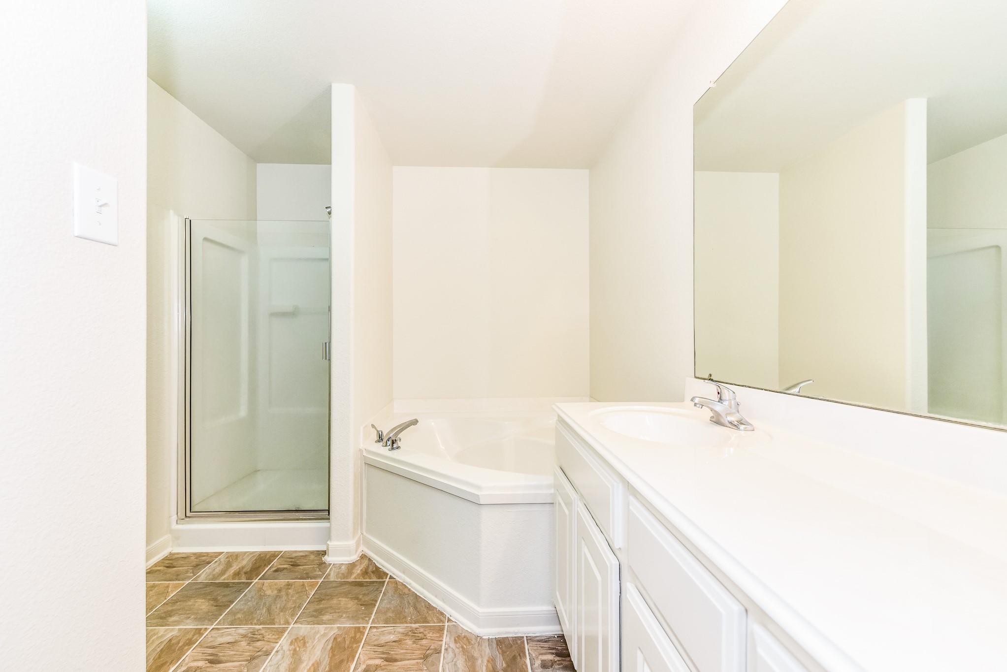 28854 Llano River Loop Spring, TX 77386 - Photo 14 of 19 This bathroom features a spacious tub, a separate glass-enclosed shower, sink with a large mirror, and tiled flooring for a modern and functional design.