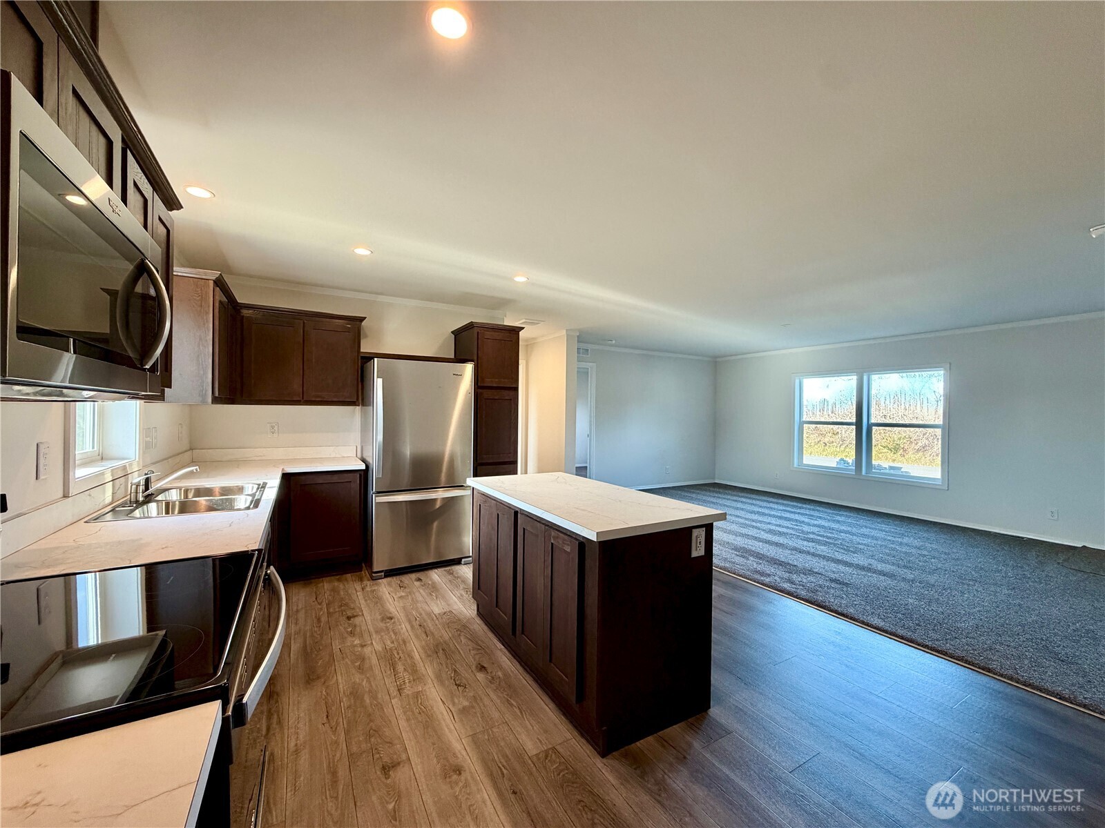 299 Octopus Avenue Northeast Ocean Shores, WA 98569 - Photo 9 of 40 a kitchen with stainless steel appliances kitchen island hardwood floor sink stove refrigerator and wooden floor