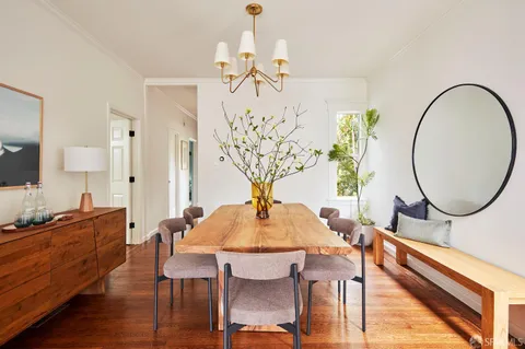 a dining room with furniture a potted plant and wooden floor
