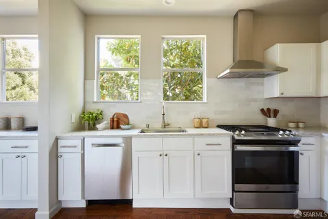 a kitchen with white cabinets and a stove with wooden floors