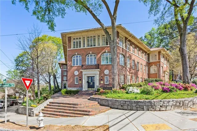 a front view of a multi story residential apartment building with yard and sign board