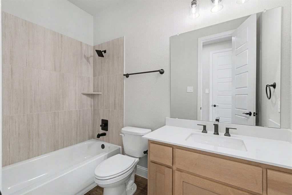 7041 Champion Road Midlothian, TX 76065 - Photo 22 of 30 a bathroom with a granite countertop sink a toilet and shower