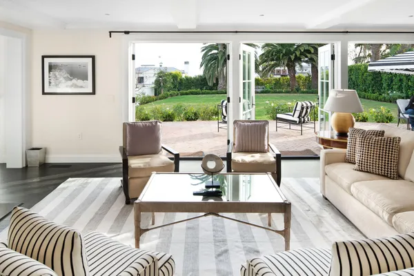 a living room with furniture large windows and wooden floor