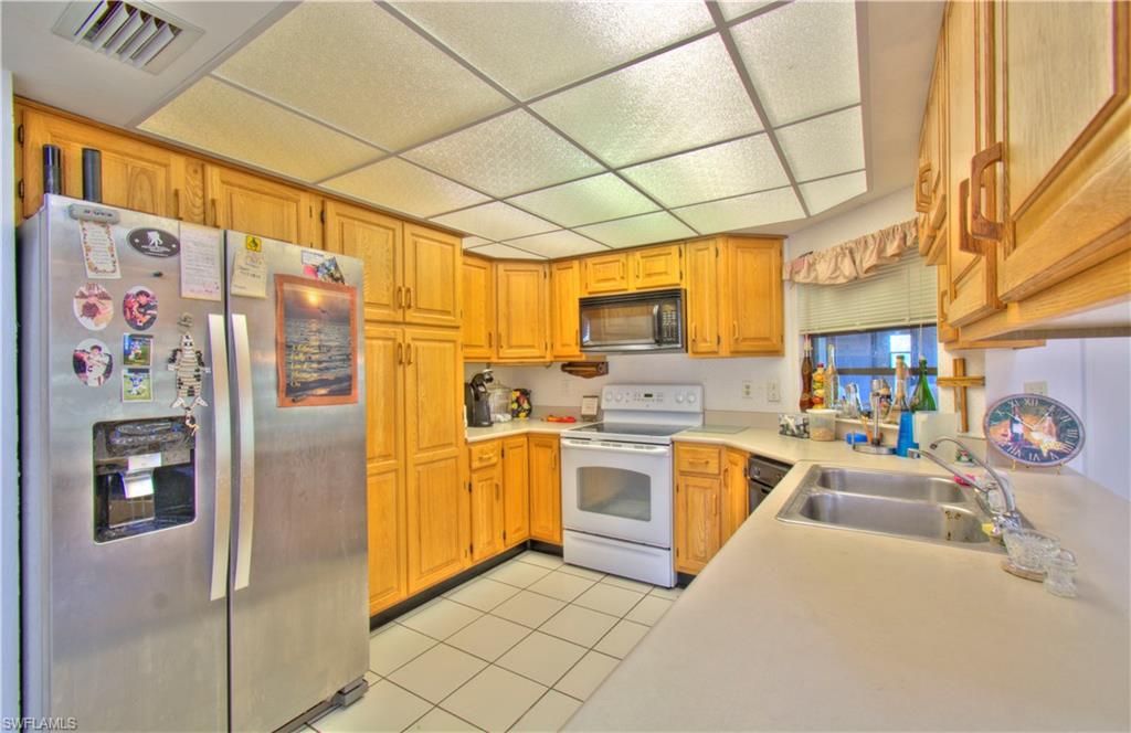 2600 Garland Road Naples, FL 34117 - Photo 14 of 34 a kitchen with stainless steel appliances granite countertop a refrigerator and a stove top oven