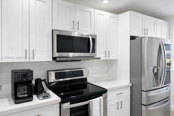 a kitchen with refrigerator a microwave a stove and cabinets
