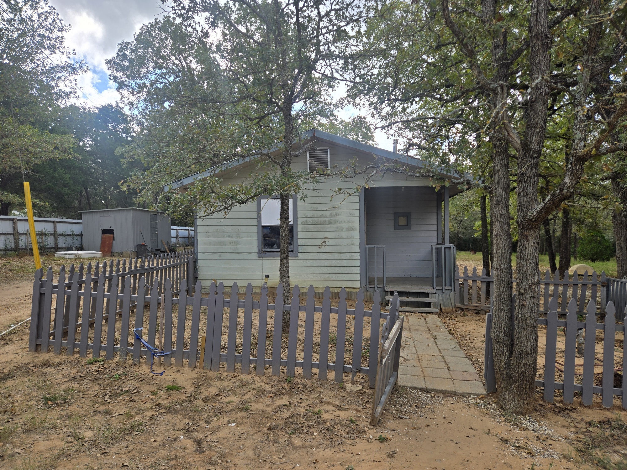 a front view of house with wooden fence and a large tree