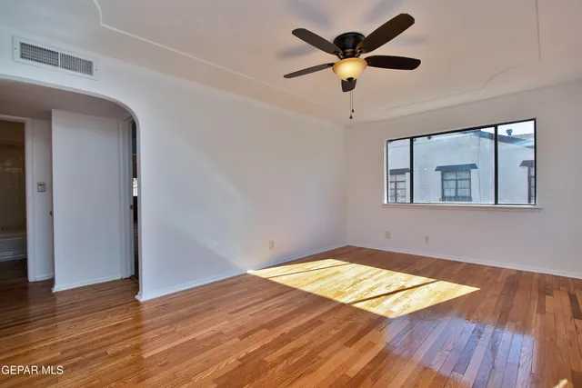 a view of empty room with wooden floor and fan