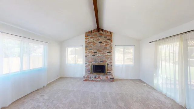 a view of an empty room with a fireplace and a window