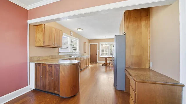 a large kitchen with granite countertop a large window and white cabinets