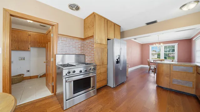a large white kitchen with cabinets a sink a window and chairs