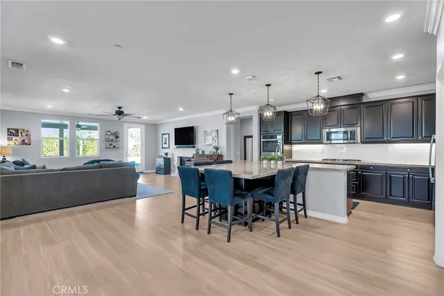 a kitchen with stainless steel appliances kitchen island granite countertop a table chairs and a refrigerator