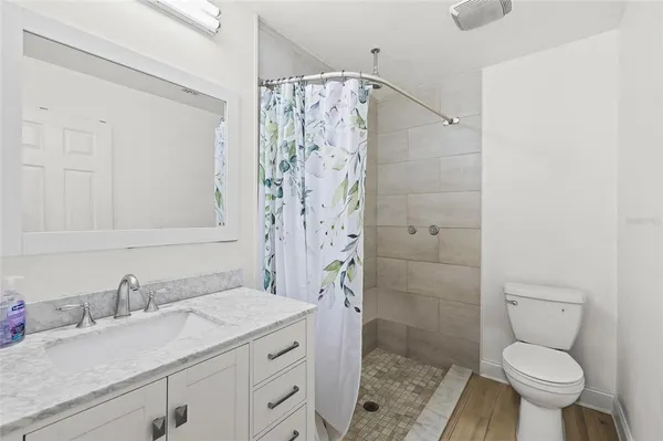 a bathroom with a granite countertop sink a toilet and shower
