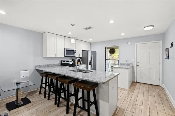 a kitchen with stainless steel appliances granite countertop a kitchen island a stove a table and chairs in it