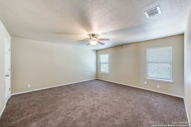 an empty room with a chandelier fan and windows