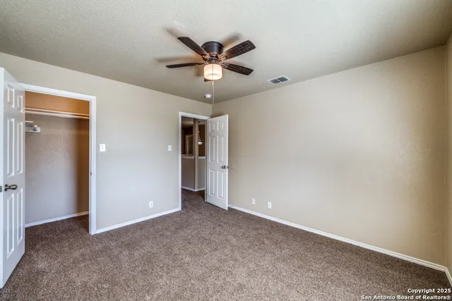 an empty room with closet and a ceiling fan