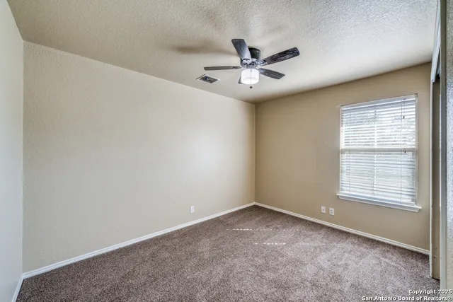 an empty room with a window and a fan