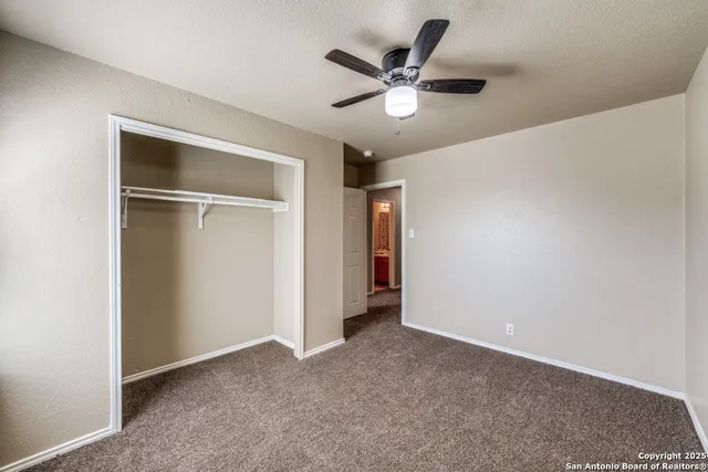 an empty room with closet and a ceiling fan
