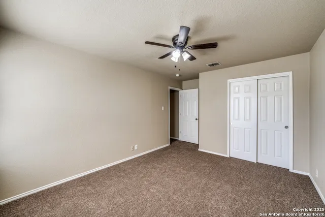 a view of an empty room and chandelier fan