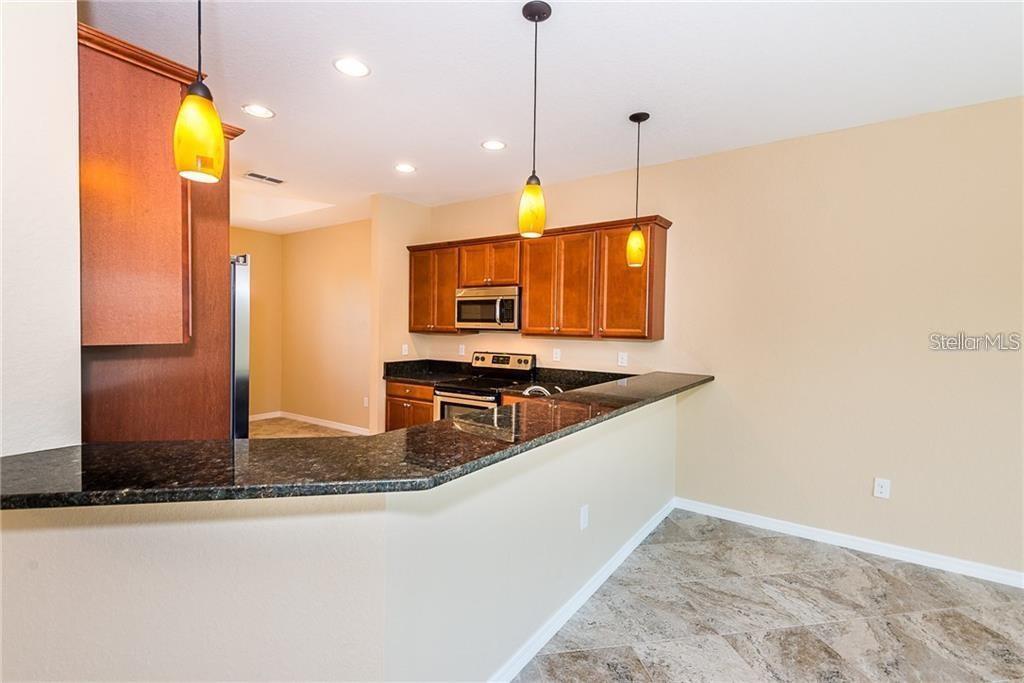 3948 San Rocco Drive, Unit 112 Punta Gorda, FL 33950 - Photo 5 of 18 a kitchen with stainless steel appliances granite countertop a sink a stove and a refrigerator