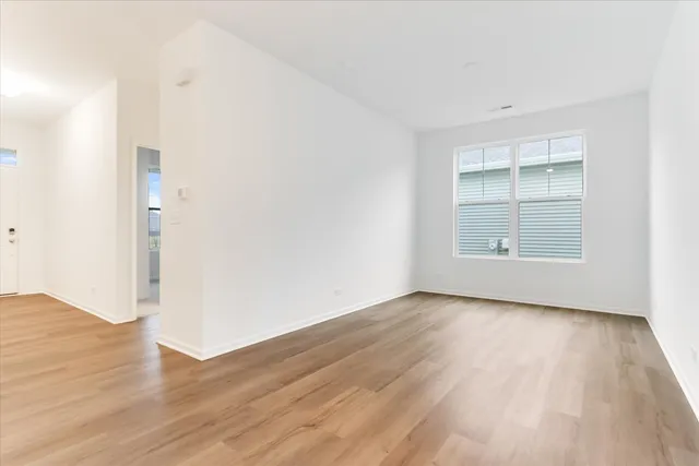 an empty room with wooden floor closet and windows