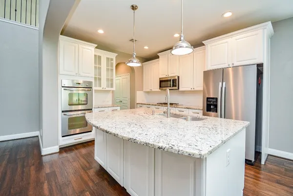 a kitchen with granite countertop kitchen island wooden floor center island and stainless steel appliances