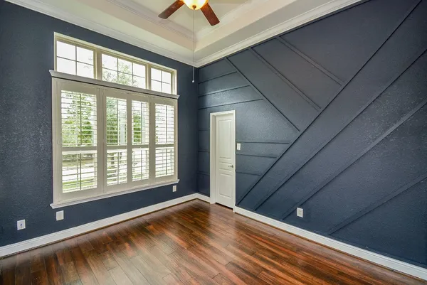 a view of an empty room with wooden floor fireplace and a window