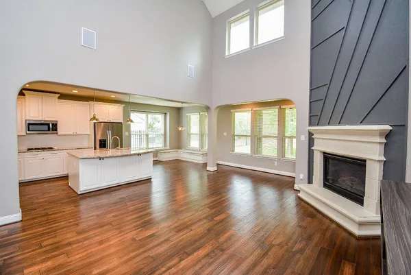 a kitchen with stainless steel appliances kitchen island granite countertop a refrigerator oven stove a sink dishwasher and white cabinets with wooden floor