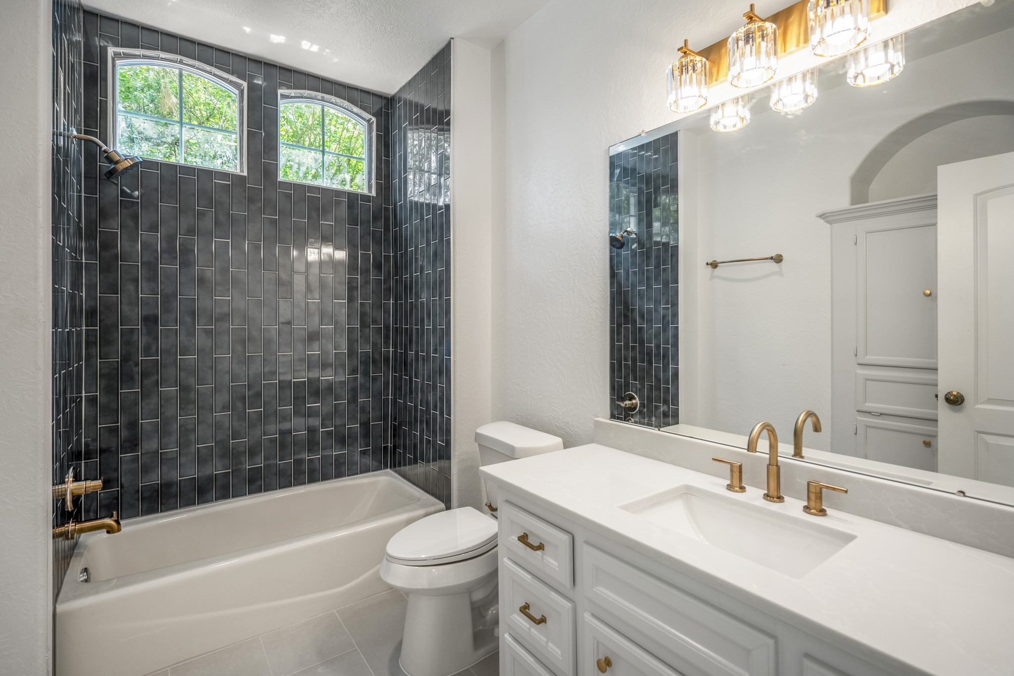 15 Lochbury Court Spring, TX 77379 - Photo 28 of 48 The upstairs bathroom has been beautifully updated and dramatic with stunning dramatic tile work, quart countertop and beautiful vanity with gorgeous lighting.