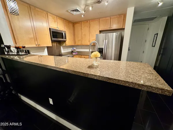 a kitchen with stainless steel appliances granite countertop a refrigerator a sink and a microwave