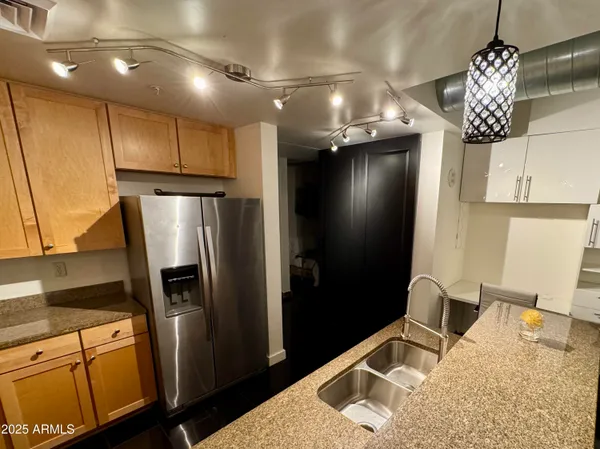 a kitchen with stainless steel appliances kitchen island granite countertop a refrigerator and a sink