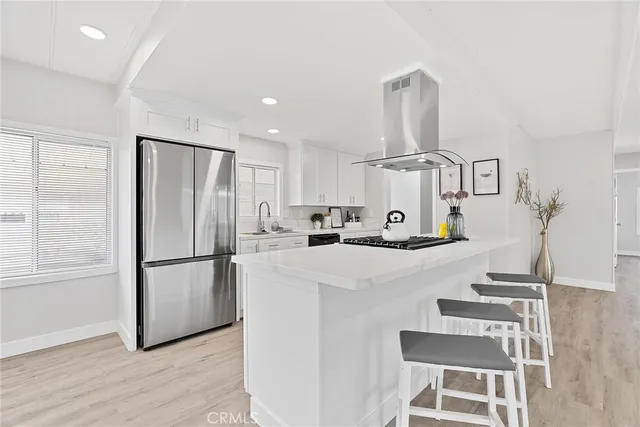 a kitchen with kitchen island a white counter top space and stainless steel appliances