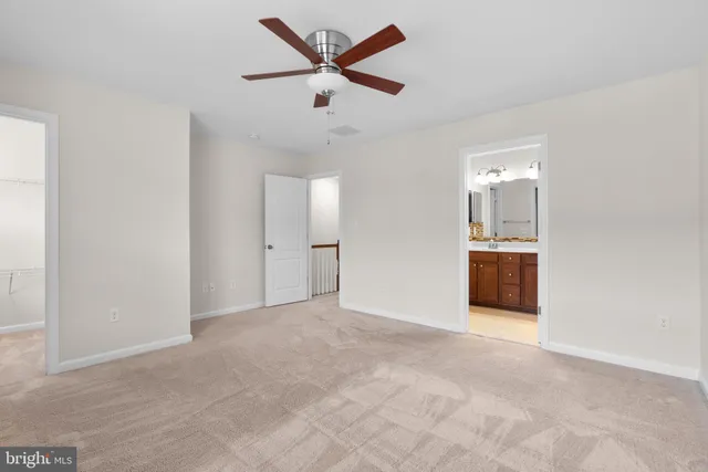 an empty room with chandelier fan and windows