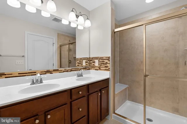 a bathroom with a double vanity sink mirror and shower