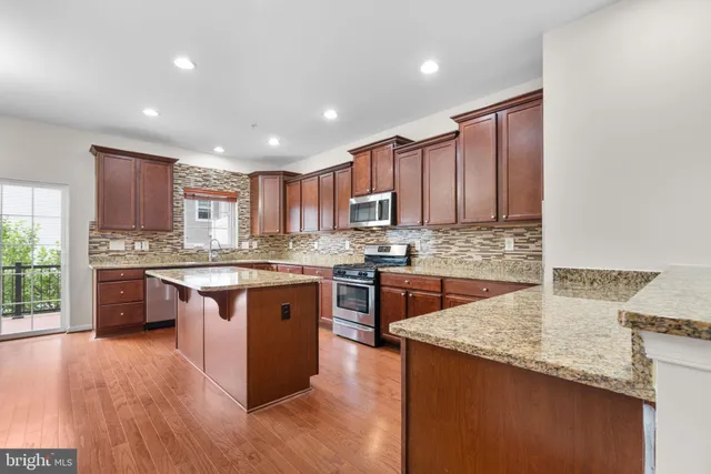 a kitchen with stainless steel appliances granite countertop wooden cabinets granite counter tops and a hard wood floors