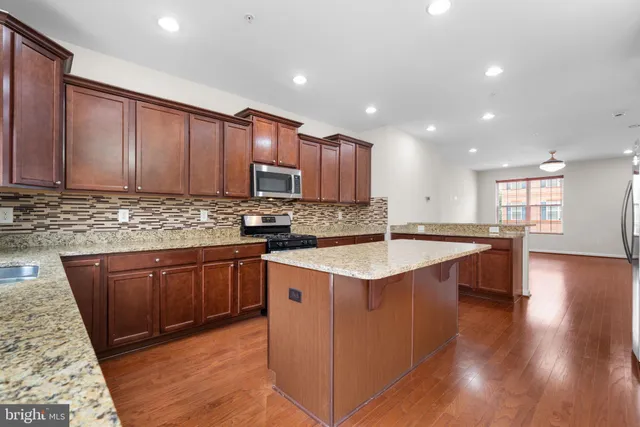 a kitchen with kitchen island granite countertop wooden cabinets a sink and a stove