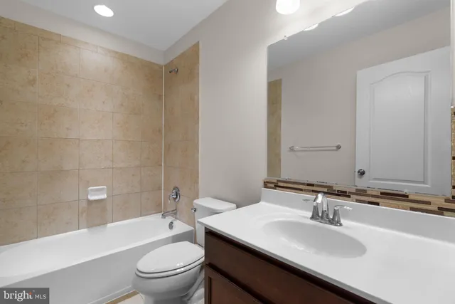 a bathroom with a bathtub shower sink mirror vanity and toilet