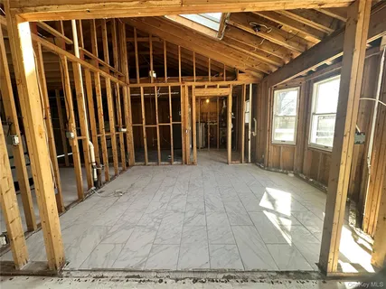 a view of an empty room with wooden floor and windows