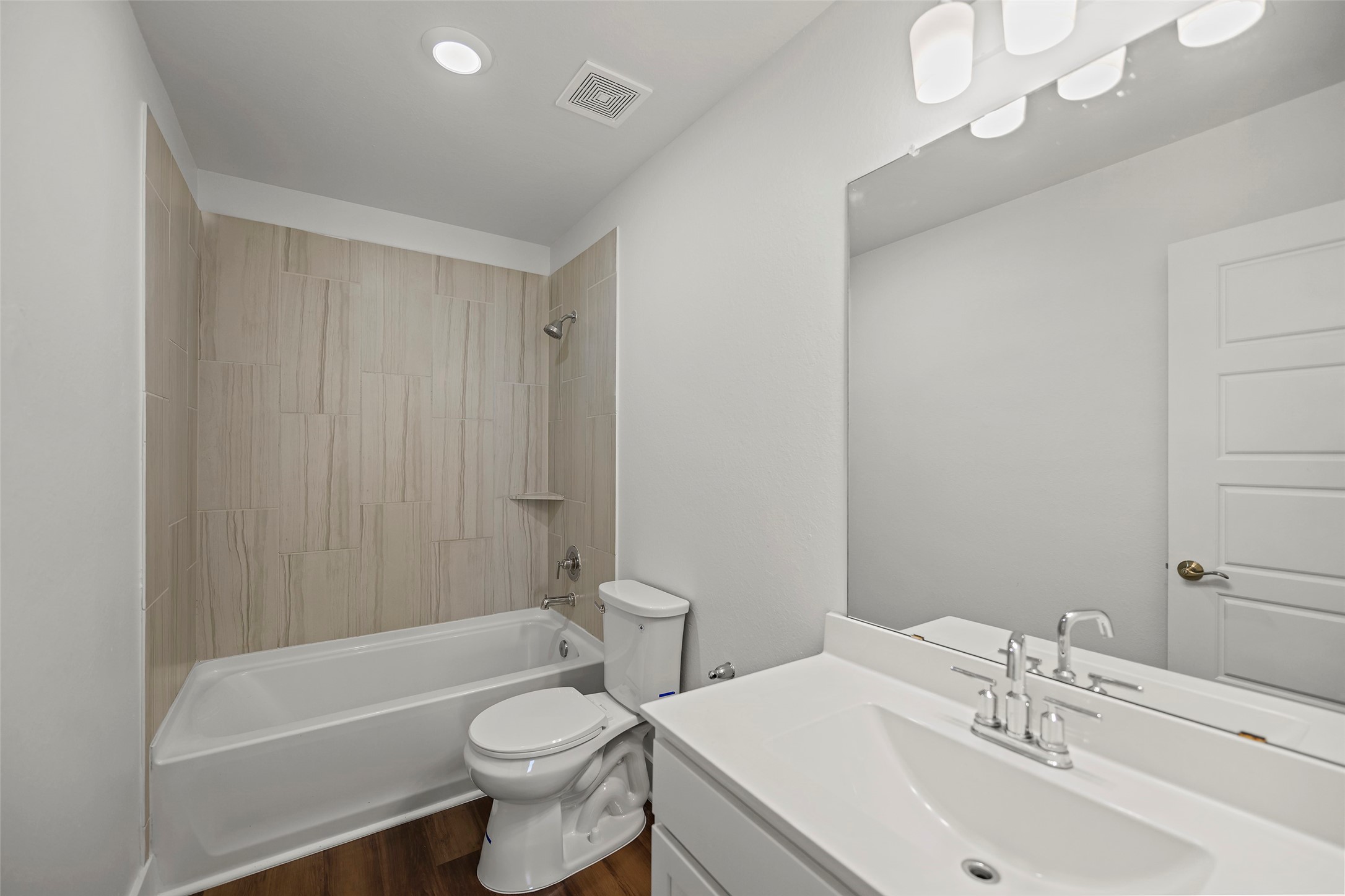 10603 Whitejacket Conroe, TX 77385 - Photo 12 of 42 Modern bathroom featuring a white vanity with a large mirror, sleek fixtures, and a shower-tub combo with neutral tile. Bright and inviting space.