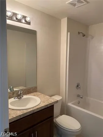 a bathroom with a granite countertop sink toilet a mirror and shower